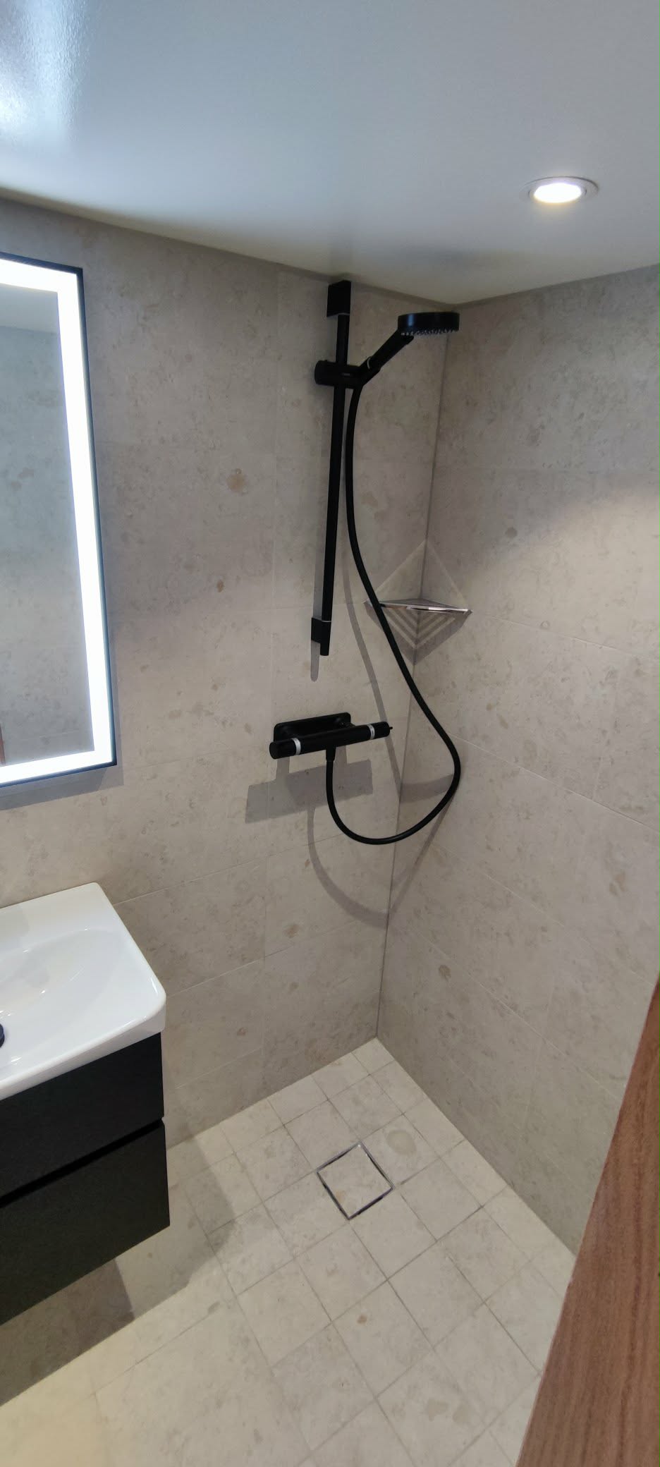 Ljusa plattor i duschutrymme med svart dusch